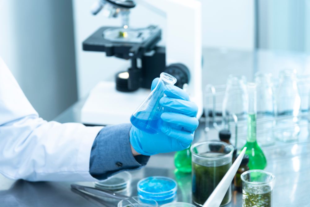 Profesional de laboratorio trabajando con material de vidrio y microscopio